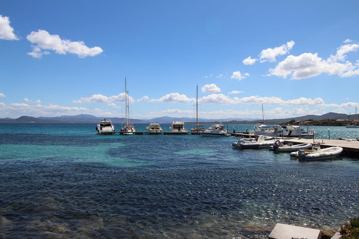 Golfo Aranci yacht harbor with calm waters, sailboats, and Sardinian coastal buildings in the background