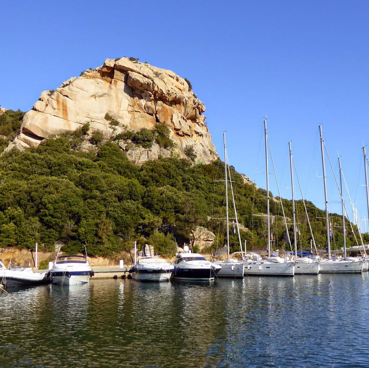 View of Poltu Quatu harbor with yachts moored in a sheltered marina inlet near Porto Cervo
