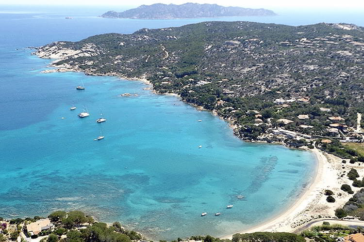 View of the beach near Marina di Puntaldia with crystal-clear water and moored yachts in Costa Smeralda, Sardinia