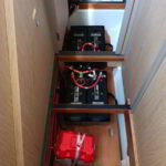 Yacht battery setup with technician checking cables and housing in engine room