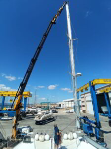 Sailing yacht undergoing dismasting operation by expert crew at marina in Northern Sardinia