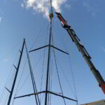 Sailing yacht undergoing dismasting operation by crane